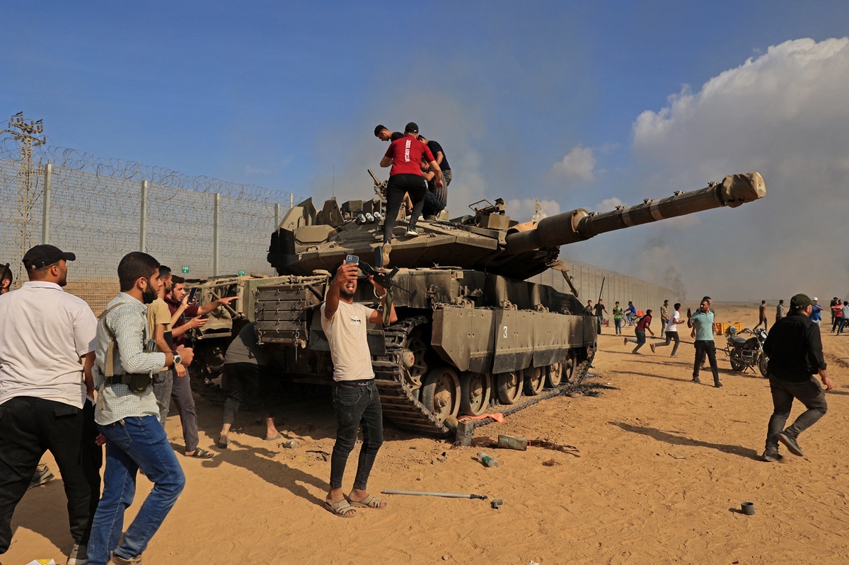 مسلحون فلسطينيون يسيطرون على دبابة إسرائيلية بعد عبور السياج الحدودي مع إسرائيل في جنوب قطاع غزة، 7 أكتوبر، 2023. المصدر (AFP)