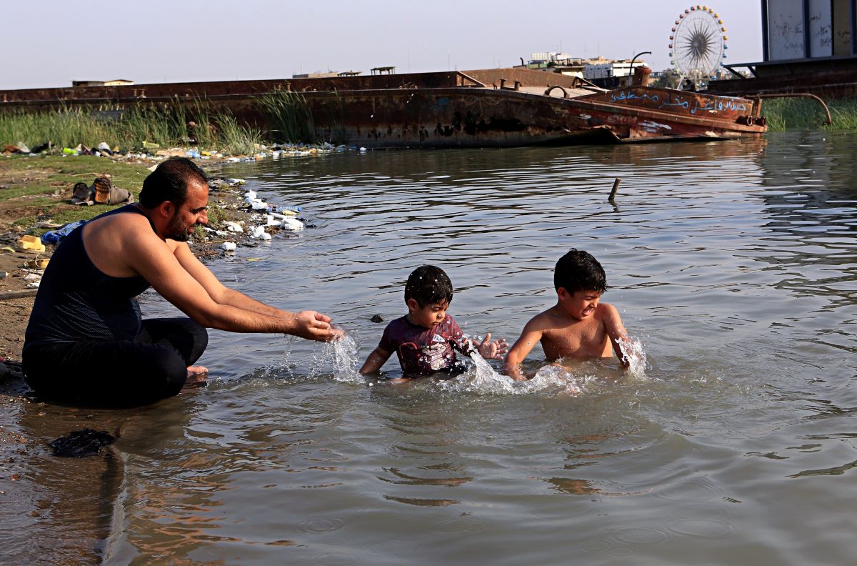 أب عراقي برفقة أبنائه على شاطئ شط العرب بمدينة البصرة... المصدر(AP)