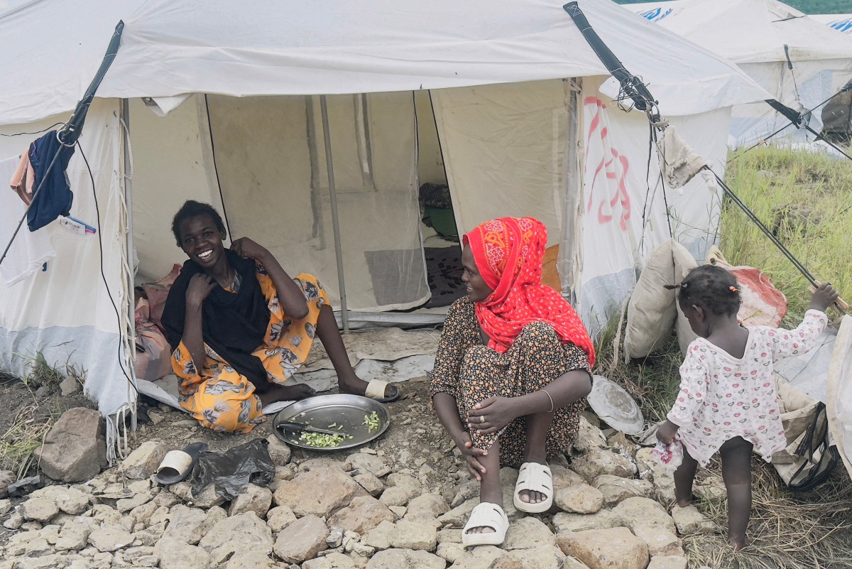 النازحون السودانيون العائدون من إثيوبيا يعدون الطعام أمام خيمتهم في مخيم تديره المفوضية السامية للأمم المتحدة لشؤون اللاجئين بمدينة القلابات، 4 سبتمبر 2024.المصدر ( AFP)