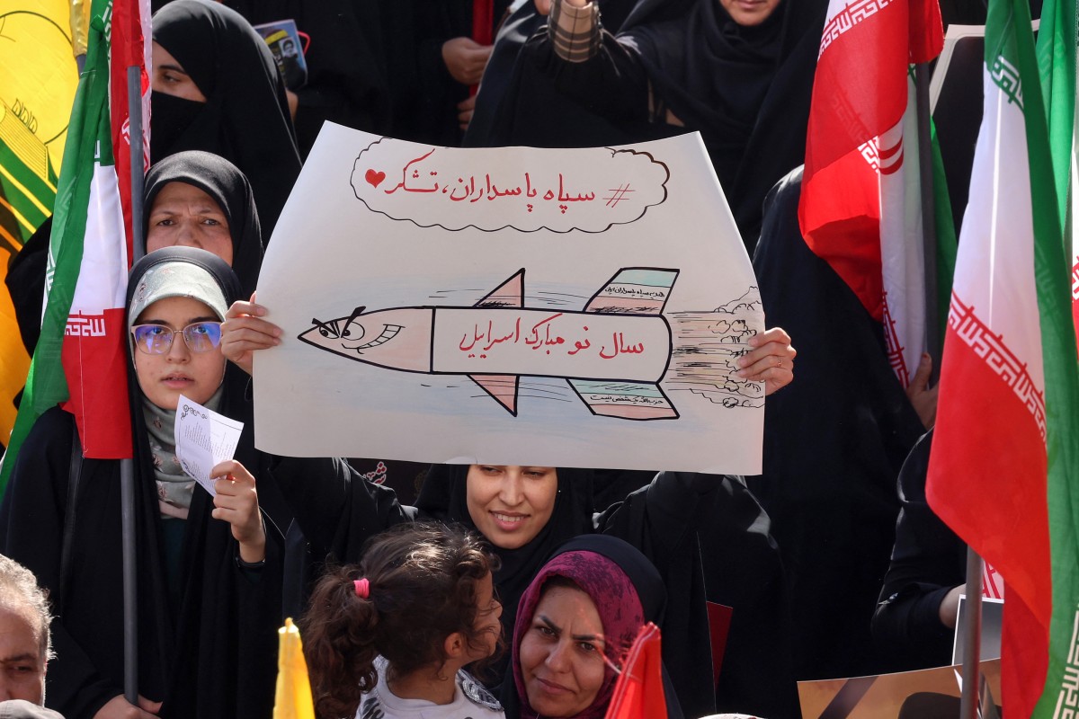 متظاهرون في طهران يحملون الأعلام ويرفعون رسمة لصاروخ بعد إطلاق إيران وابلًا من الصواريخ نحو إسرائيل (2 أكتوبر 2024). (وكالة الصحافة الفرنسية)
