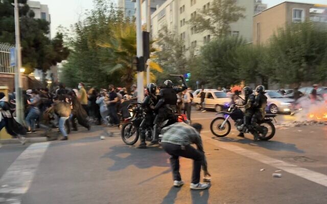 A picture obtained by AFP outside Iran shows an Iranian police officer (C) raising a baton to disperse demonstrators during a protest for Mahsa Amini, a woman who died after being arrested in Tehran on September 19, 2022. (AFP)

