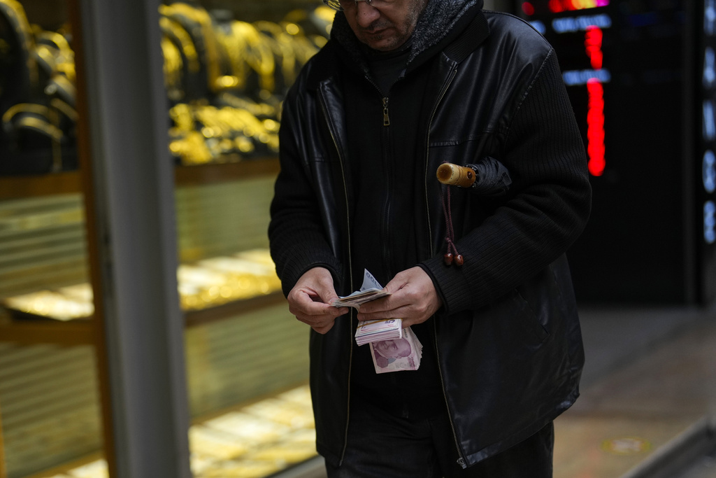 A man holds Turkish Liras banknotes outside an exchange currency shop in Eminonu commercial area in Istanbul, Turkey, Thursday, Jan. 25, 2024. (AP Photo/Francisco Seco)