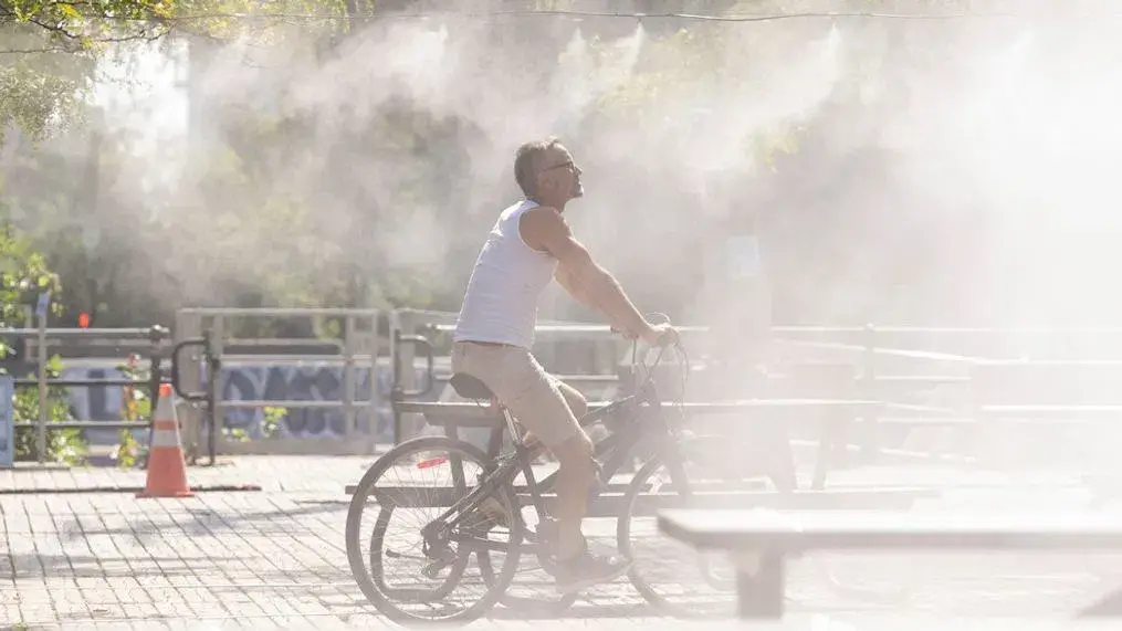A man cycles through a mister to cool off from the heat in Montreal, Sept. 6, 2023. Photo: AP