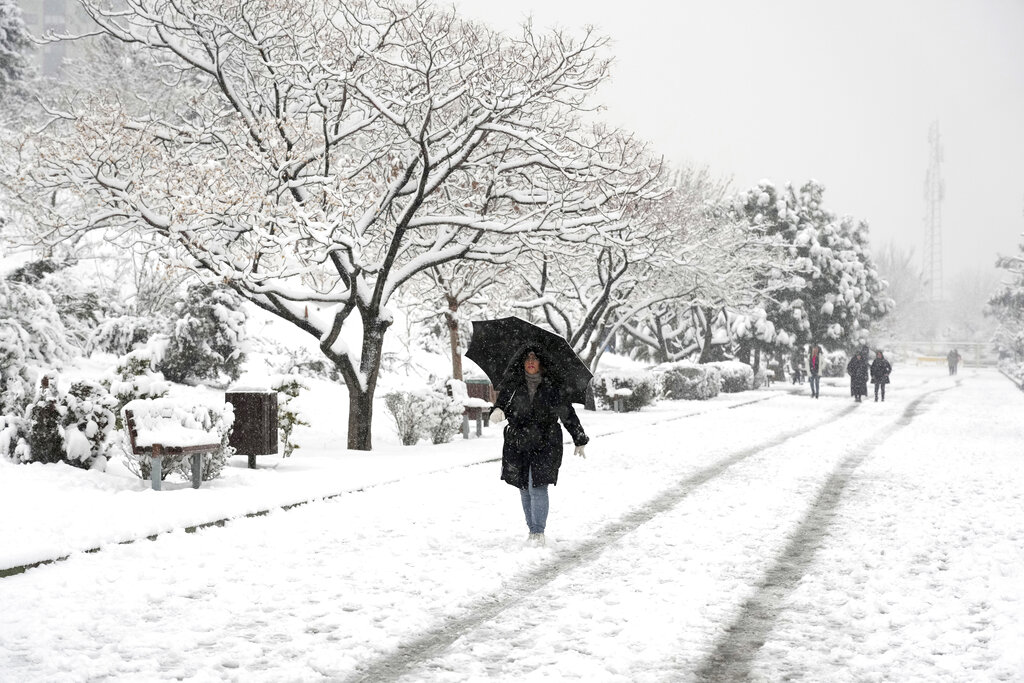 A woman walks in the snow at Pardisan Park in Tehran, Iran, Sunday, Feb. 12, 2023. Some citizens took the opportunity to enjoy the snow and the clean air, while the country is struggling with decades-long drought. (AP Photo/Vahid Salemi)