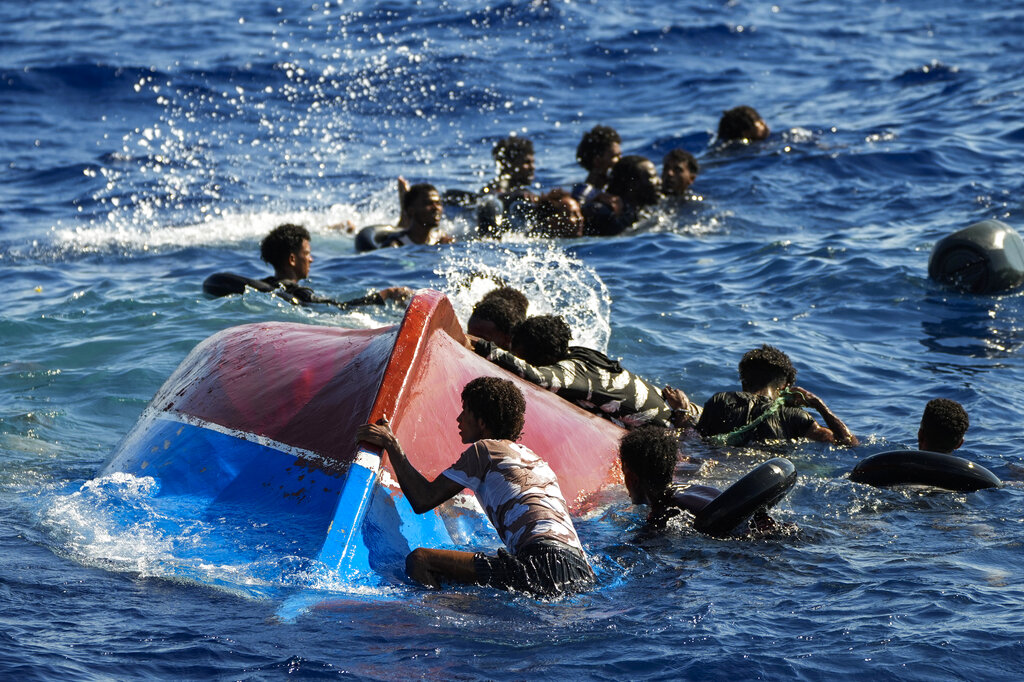 FILE - Migrants swim next to their overturned wooden boat during a rescue operation by Spanish NGO Open Arms at south of the Italian Lampedusa island at the Mediterranean sea, Thursday, Aug. 11, 2022. (AP Photo/Francisco Seco, File)