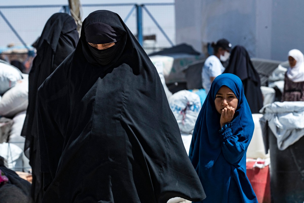 A woman and child walk in the the al-Hol camp in Syria's northeastern Al-Hasakah Governorate on July 28, 2024, as Syrian families of suspected Islamic State fighters prepare to return to their homes in the countryside of Deir Ezzor. - The al-Hol camp is the largest of two in northeastern Syria holding the families of Islamic State fighters. Run by US-backed Kurdish-led Syrian Democratic Forces (SDF), its population spiked at more than 70,000 as the coalition began tightening its grip on the last IS holdout in Baghouz late in 2018. (Photo by Delil SOULEIMAN / AFP)