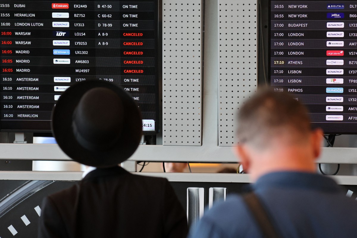 Passengers look at the flight board at Ben Gurion airport near Tel Aviv on August 6, 2024, amid regional tensions during the ongoing war between Israel and the Palestinian Hamas movement in the Gaza Strip. - The United States said it was working "around the clock" to avert an all-out war in the Middle East, as Israel remained on high alert for potential Iranian retaliation for two high-profile killings. (Photo by GIL COHEN-MAGEN / AFP)