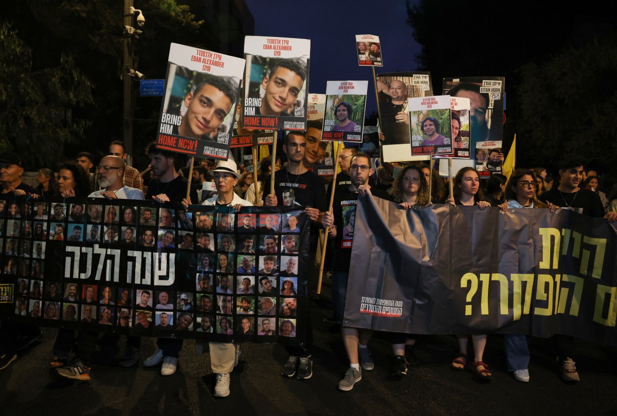 Relatives and supporters of Israeli hostages taken by Palestinian militants on the October 7 Hamas attack and held in Gaza, hold images of their loved ones during a protest calling for their release in front of Prime Minister Benjamin Netanyahu residency in Jerusalem on October 7, 2024. (Photo by Menahem KAHANA / AFP)