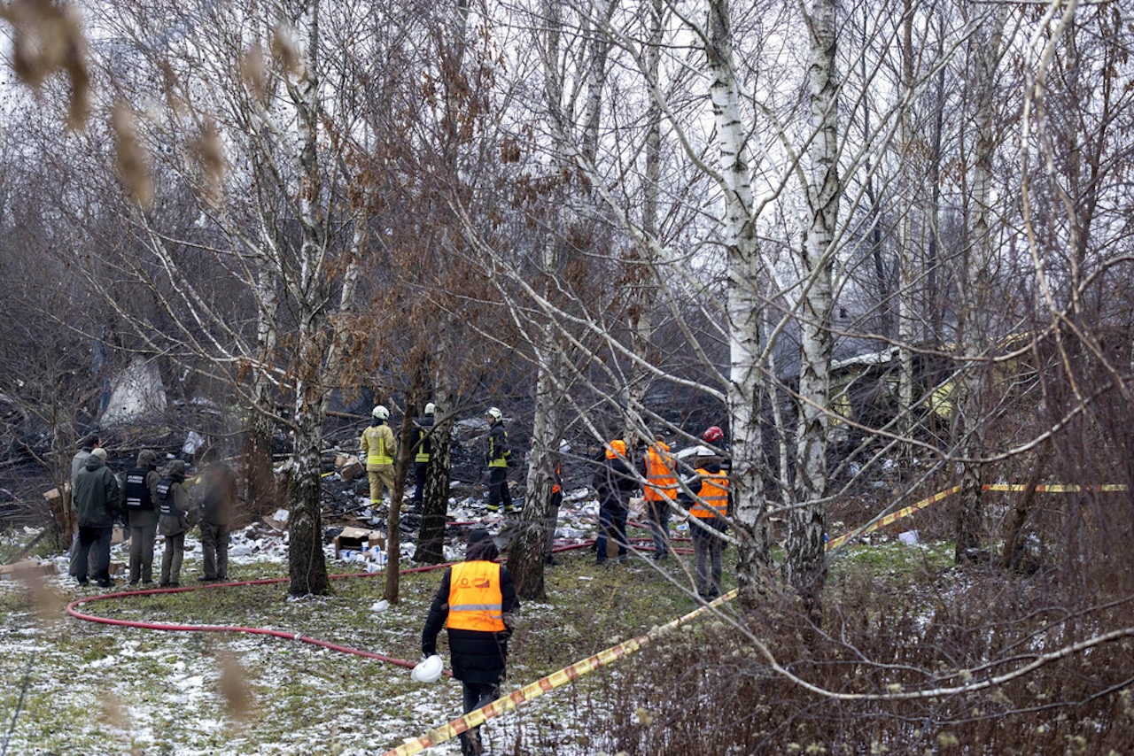 Lithuanian Emergency Ministry employees work near the place where a DHL cargo plane crashed into a house near the Lithuanian capital Vilnius, Lithuania, Monday, Nov. 25, 2024. (AP Photo/Mindaugas Kulbis)