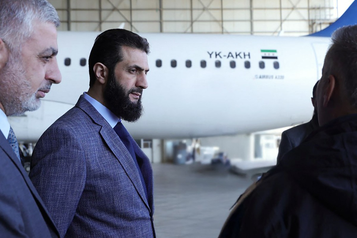 This handout picture released by the official Syrian Arab News Agency (SANA) on January 7, 2025, shows Syria's de facto leader Ahmed al-Sharaa (C) talking to officials during a visit at Damascus International Airport. (Photo by SANA / AFP) / 