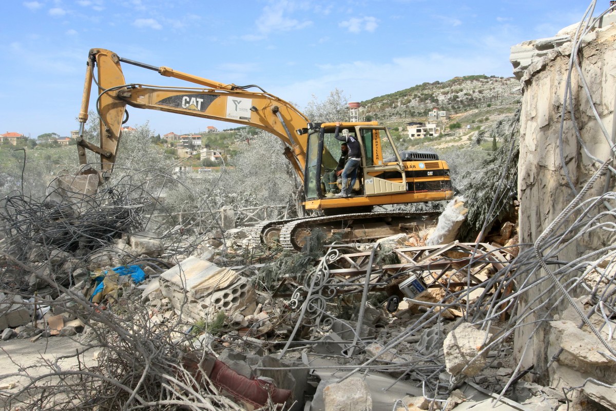 An excavator removes wreckage at site of an Israeli airstrike that targeted a house in the southern Lebanese village of Kfar Tibnit on March 28, 2025. (Photo by Mahmoud ZAYYAT / AFP)
