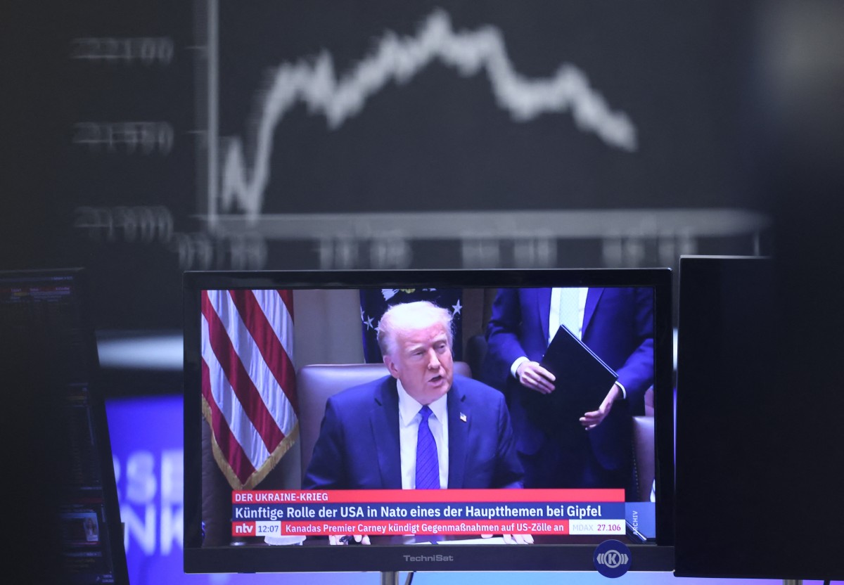 US President Donald Trump is seen on a TV screen below a display showing the German Stock Market Index DAX at the stock exchange in Frankfurt, Germany, on April 3, 2025. (Photo by Daniel ROLAND / AFP)