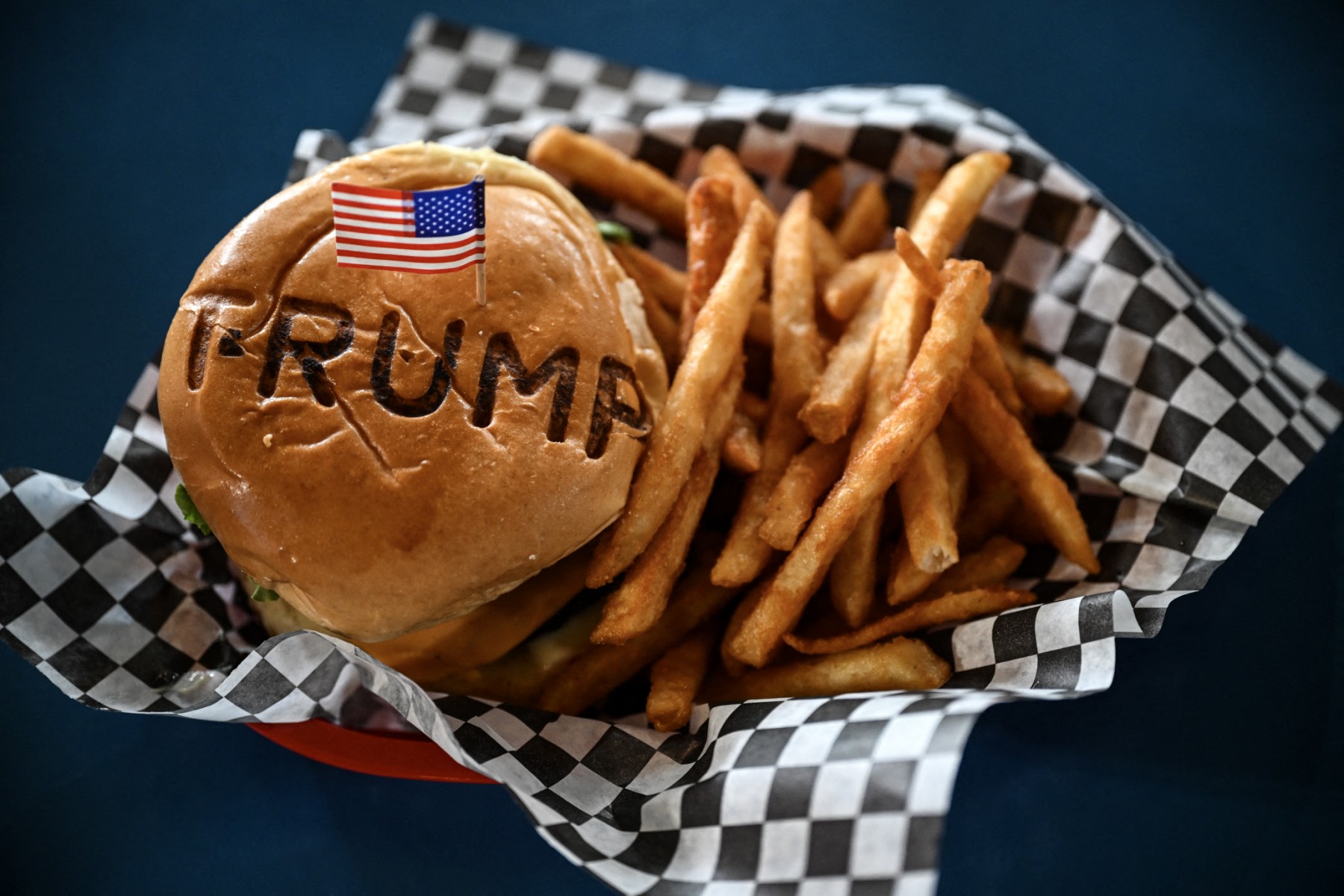A burger is seen at Trump Burger restaurant, in Bellville, Texas, on April 19, 2025. It is lunchtime at a Texas eatery called Trump Burger and diners are enjoying fast food and the frenetic first 100 days of their president's second term. Trump is everywhere in this joint with a dozen tables -- in cardboard cutouts of the man eking out his trademark forced smile, on banners from the 2024 campaign, and on hats and T-shirts displayed for sale. (Photo by RONALDO SCHEMIDT / AFP)