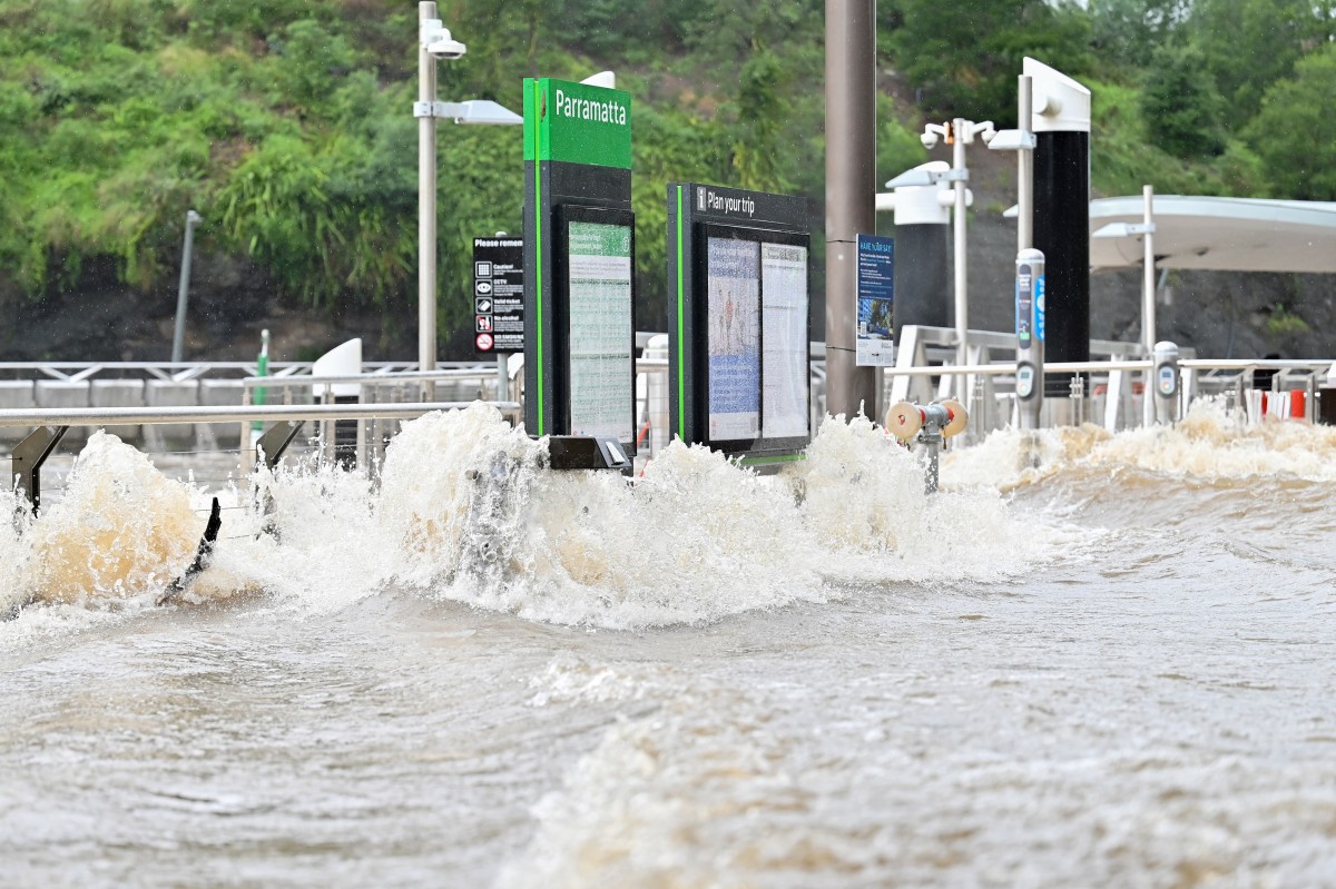 Flood water is seen flowing through Parramatta Wharf in Sydney on May 23, 2025. Record floods cut a destructive path through eastern Australia on May 23, caking houses in silt, washing out roads and separating 50,000 people from help. (Photo by Ayush Kumar / AFP)
