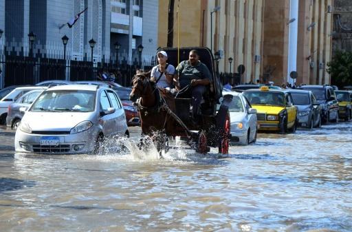 AFP/STR - Egyptian men ride a horse carriage in a flooded street in Egypt's northern coastal city of Alexandria, following heavy rains