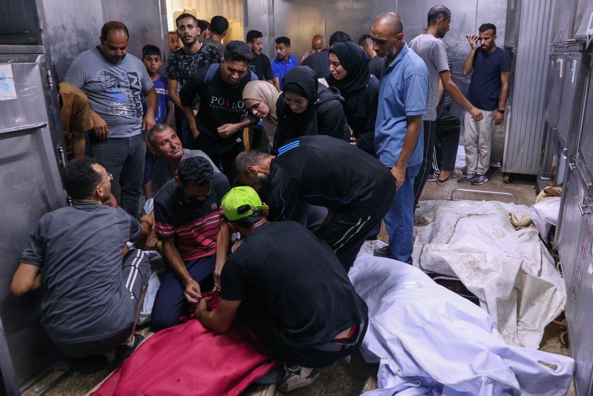Palestinians mourn by bodies of relatives killed in an Israeli strike on Al-Baqa cafeteria on Gaza City seafront, at the city's Al-Shifa hospital on June 30, 2025.