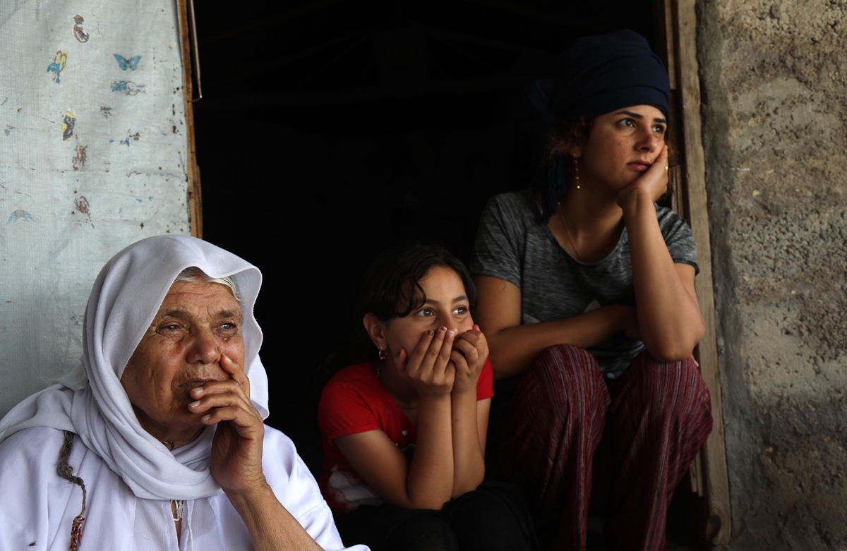 Displaced Yazidi women sit outside a tent at a camp in Khanke, Dohuk Province, on June 24, 2019. Photo: Safin Hamed / AFP 
