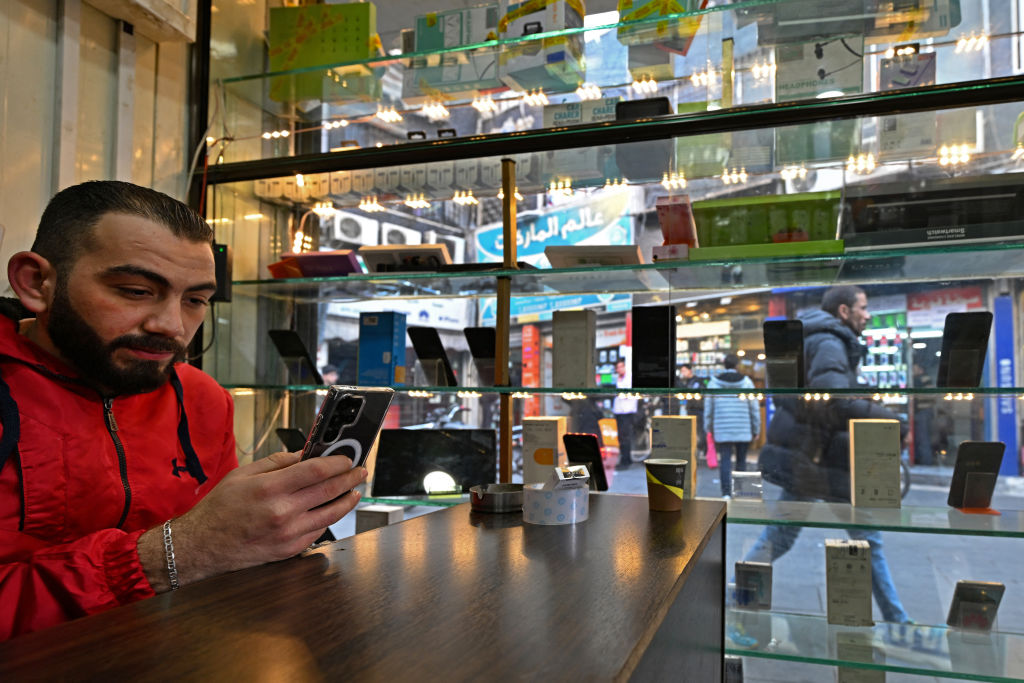 A vendor uses his mobile phone while waiting for customers at his mobile shop in the Damascus Tower market, which specializes in the smart phone business, in the Syrian capital on January 12, 2025. Photo: AFP