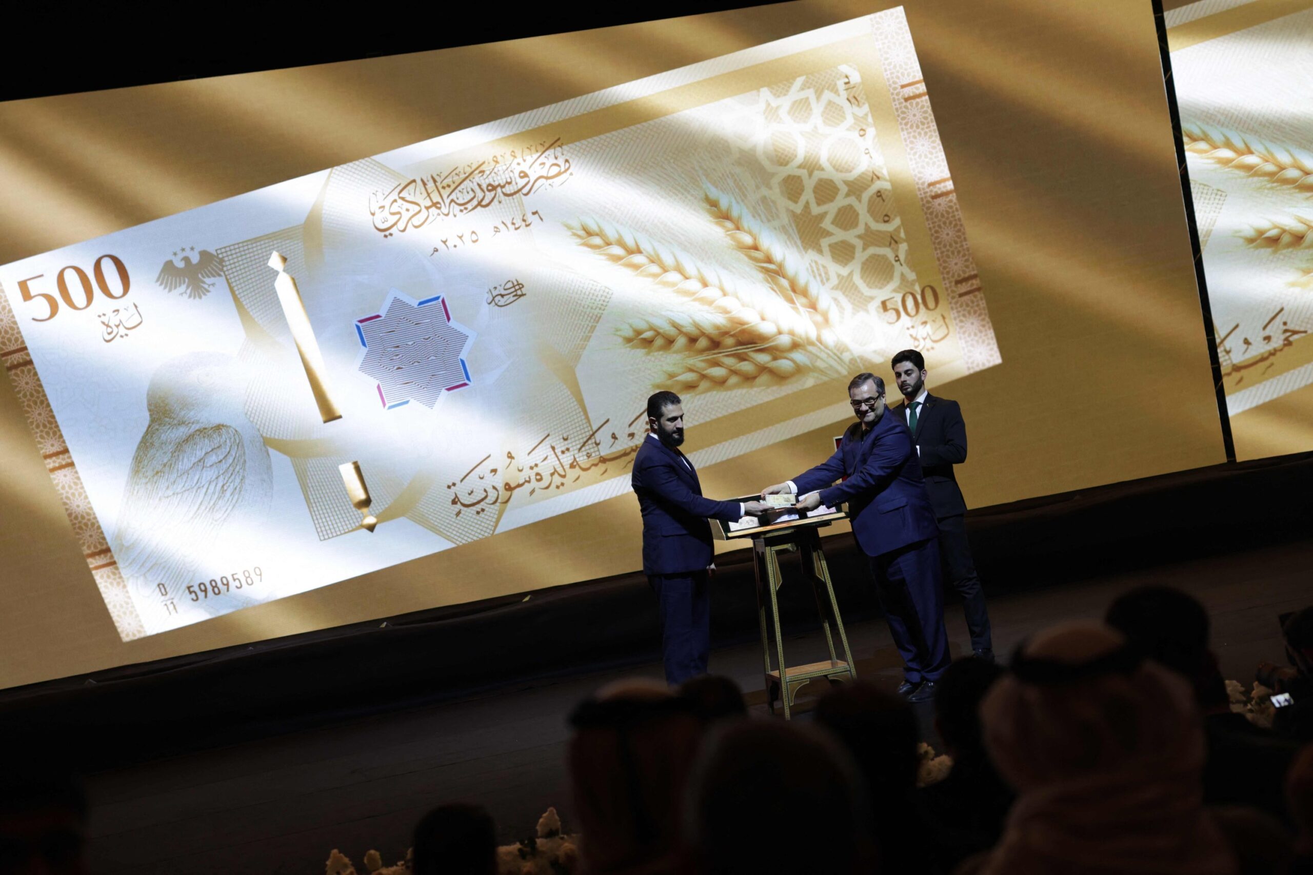 Syria's President Ahmed al-Sharaa (L) and Syria's Central bank chief Abdul Qadir al-Hasriya (R) hold one of the country's new revamped currency notes at the Conference Palace in the capital Damascus, Syria, Dec. 29, 2025. Photo: AFP
