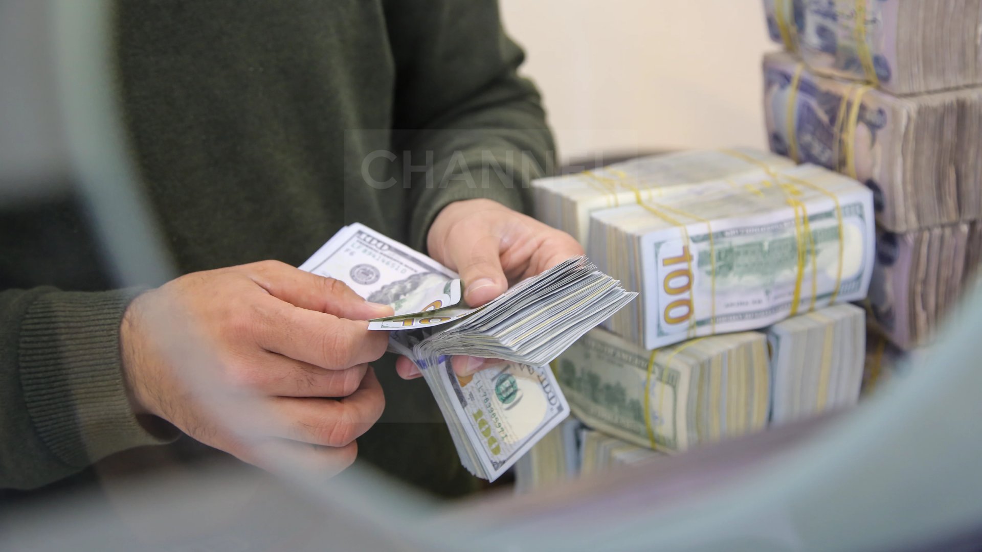 A citizen is counting dollars, with stacks of Iraqi dinars visible behind him. Photo: Hama Sur / Channel8


