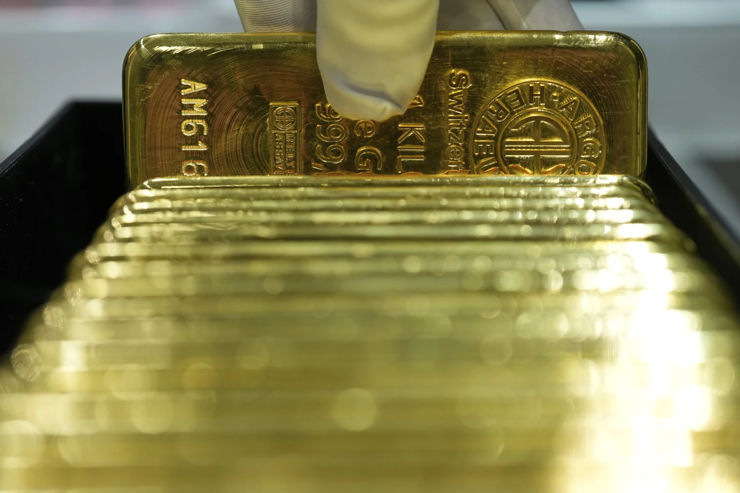 An employee of Pro Aurum gold house lifts 1 Kg gold bars of 999.9 purity in the safe deposit boxes room in Munich, Germany, Friday, April 25, 2025. (AP Photo/Matthias Schrader)