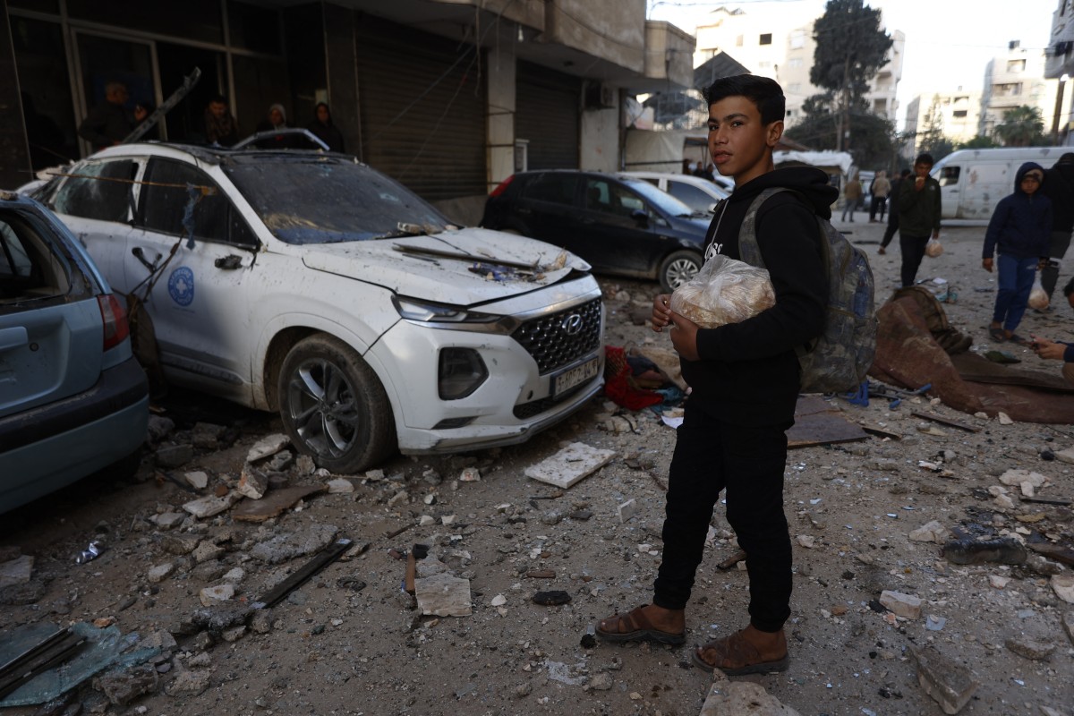 A Palestinian boy carries a bag of bread as he walks past the site following an Israeli strike on Gaza City on January 31, 2026.
 