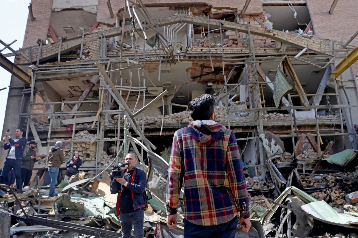 Media representatives gather around the damaged building of the Shahid Beheshti University following a strike, in Tehran on April 4, 2026. US-Israeli strikes have hit more than 30 universities across Iran since the war broke out in late February, Iran's science minister said on April 4. (Photo by AFP) /