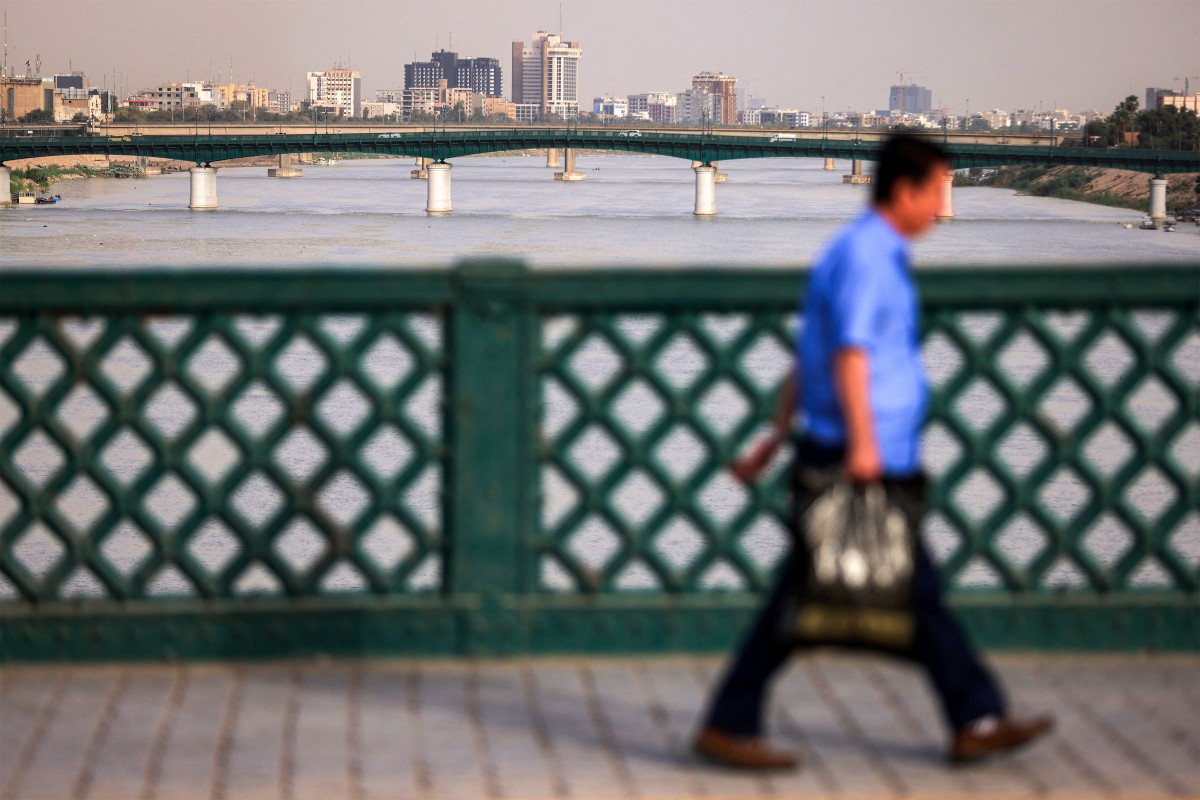 A man crosses the Ahrar Bridge along the Tigris river in central Baghdad on May 4, 2026. The Tigris' water levels have risen due to the rains and floods that have swept across Iraq this winter after years of drought caused by low rainfall. Iraq's water ministry said the reservoirs along the river are almost full, adding that it expects water levels in the Euphrates to rise in the coming days if Syria releases water from its dams. (Photo by AHMAD AL-RUBAYE / AFP)