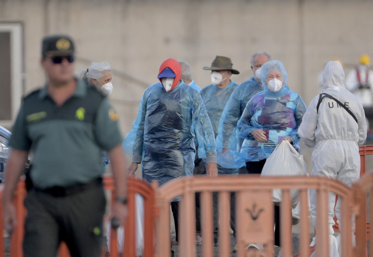 Passengers of the hantavirus-stricken cruise ship MV Hondius wait to board buses after disembarking in the port of Granadilla de Abona on the island of Tenerife in Spain's Canary Islands on May 11, 2026. Adverse weather conditions forced the cruise ship MV Hondius hit by a deadly hantavirus outbreak and anchored off Spain's Canary Islands to dock at Tenerife on May 11, 2026 before evacuations can be completed, the health ministry said. (Photo by JORGE GUERRERO / AFP)