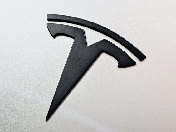 This photograph taken on May 22, 2026 shows a Tesla logo on the body of a car belonging to an electric car rental company parked in Warsaw. (Photo by Sergei GAPON / AFP)