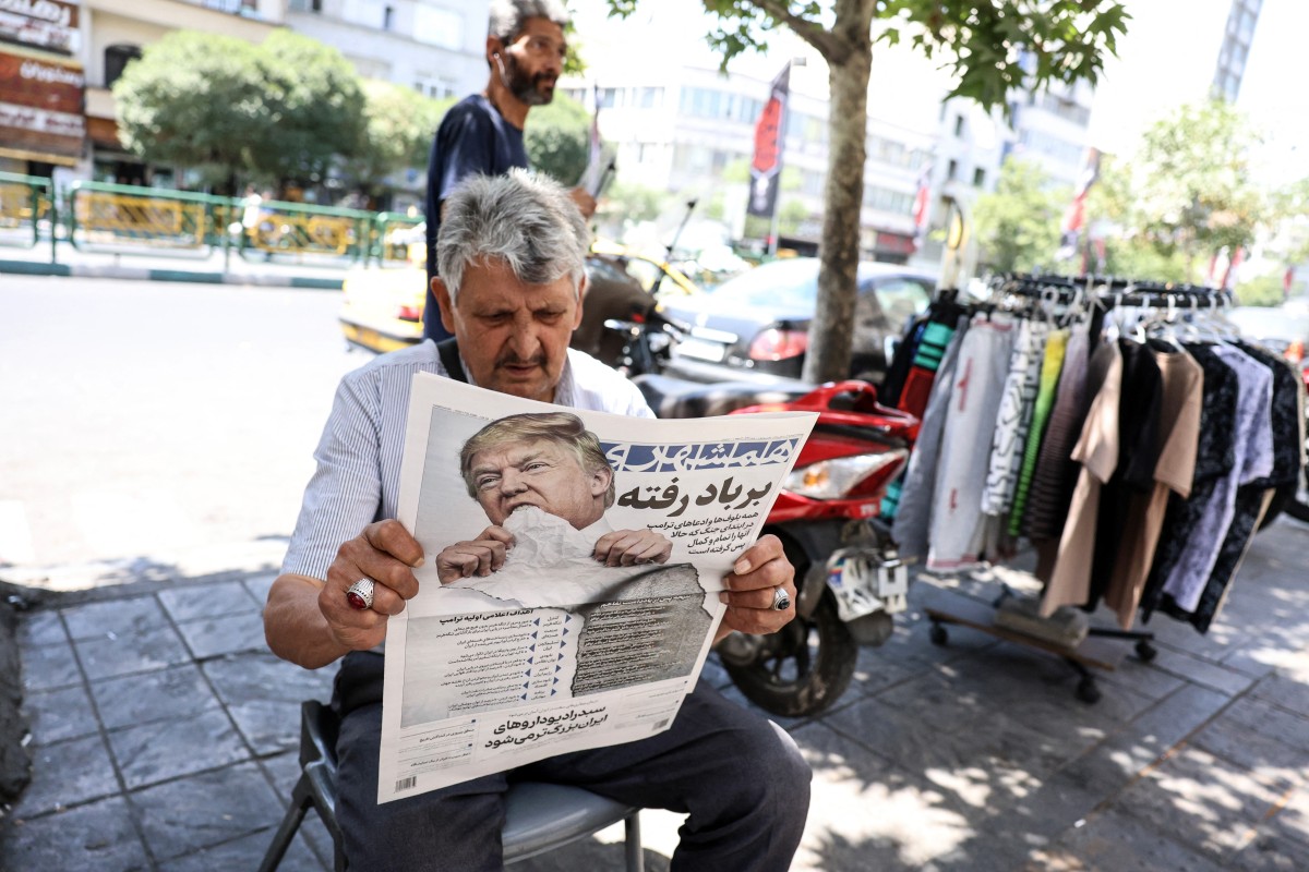 A man reads a copy of the Iranian daily newspaper Hamshahri bearing an image of the US president and a headline that reads "Gone with the wind" at a kiosk in Tehran on June 18, 2026.
