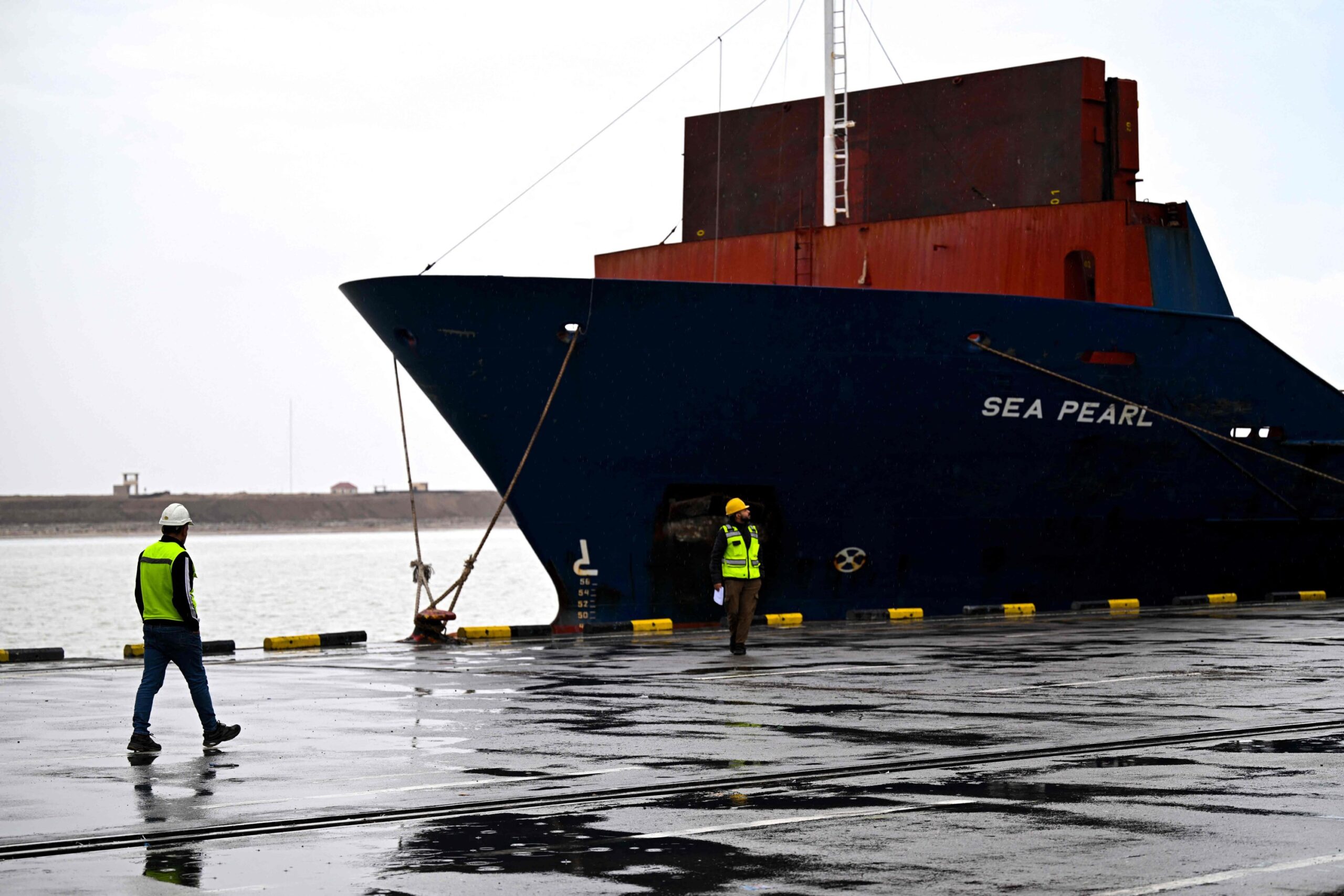 Maritime logistics operators pass by a container vessel at the Port of Umm Qasr, Basra, Iraq, March 12, 2026. Photo: AFP Photo 
