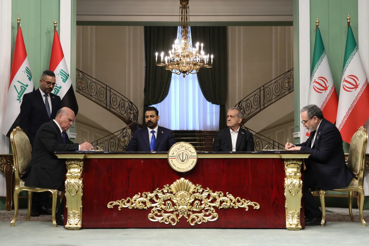 A handout photograph provided by the Iranian presidential office shows Iraq's Foreign Minister Fuad Hussein (L) and Iran's Foreign Minister Abbas Araghchi (R) signing documents as Iraq's Prime Minister Ali al-Zaidi (C-L) and Iran's President Masoud Pezeshkian (C-R) watch during a meeting in Tehran on July 23, 2026. The Iraqi prime minister is visiting Iran following a trip to the US where he met with the US president. Washington and Tehran are Iraq's main allies, but their enmity has long turned the country into a proxy battleground and left successive governments struggling to maintain a delicate balance between the foes, who have traded intensifying attacks in recent days. (Photo by IRANIAN PRESIDENCY / AFP) /