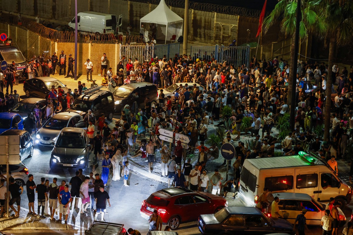 Hundreds of people were converging on Morocco's northern town of Fnideq on July 30 evening, following rumours that the border with Spain's Ceuta had opened, according to an AFP journalist. Spain had earlier reported nine deaths after hundreds of migrants entered the north African exclave from Morocco, mainly by swimming. (Photo by Abdelmajid BZIOUAT / AFP)