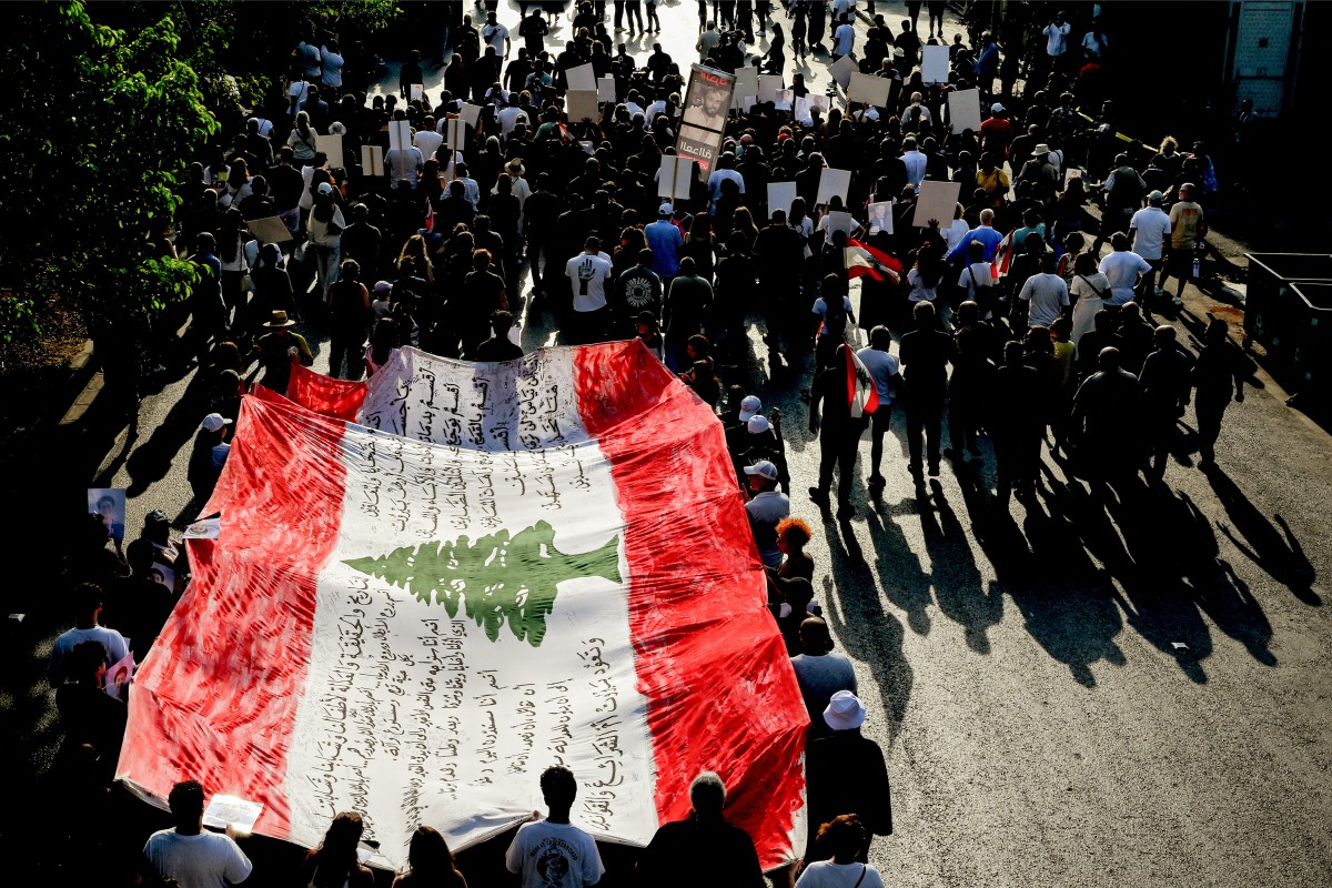 Family members and relatives of the victims of the 2020 Beirut port explosion march with a giant Lebanese flag on the sixth anniversary of the incident near the port area in Beirut on August 4, 2026. (Photo by Joseph EID / AFP)