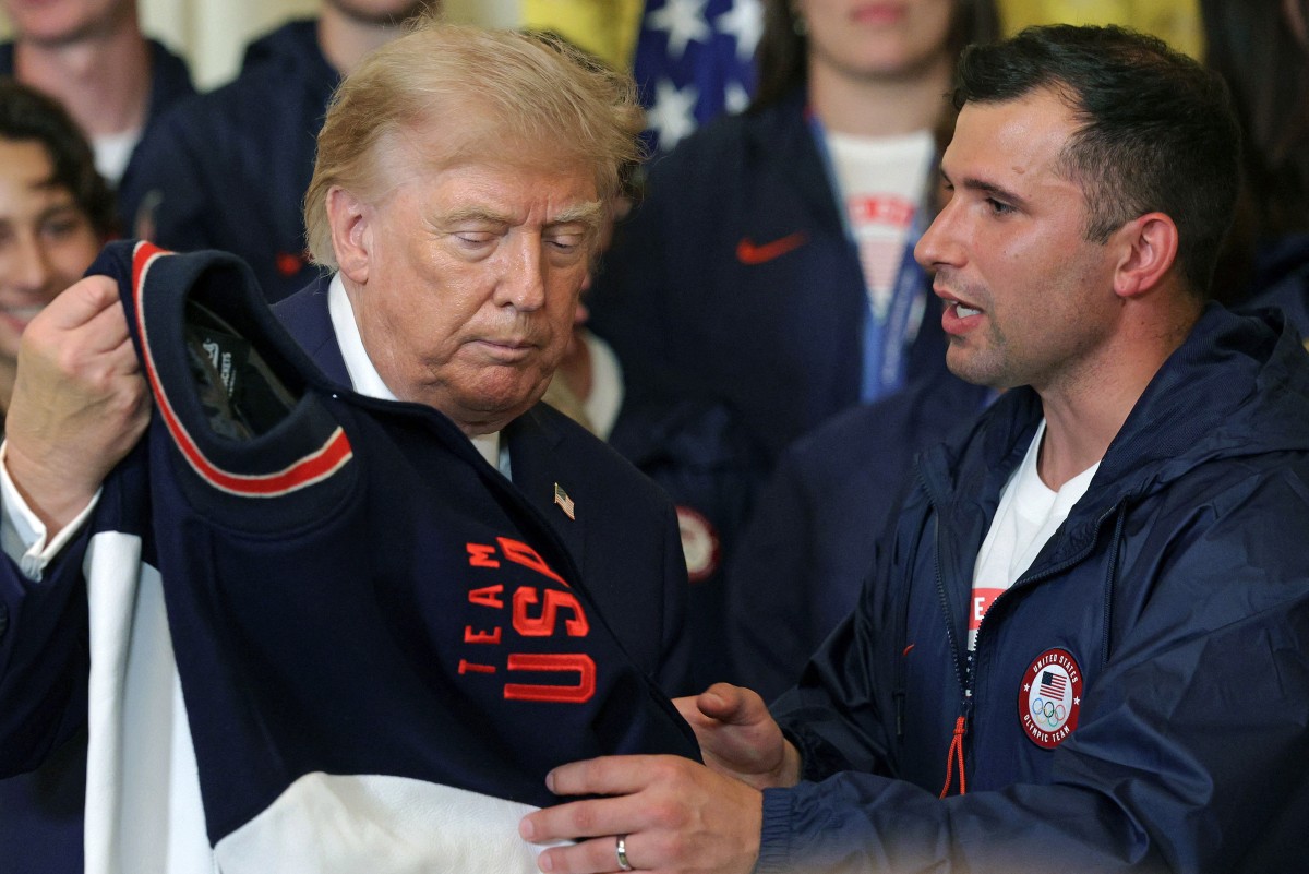 Olympic bobsledder and flag bearer Frank Del Duca (R) presents a jacket to U.S. President Donald Trump (L) at a reception for Team USA for the 2026 Winter Olympic and Paralympic Games at the East Room of the White House on August 6, 2026 in Washington, DC. 