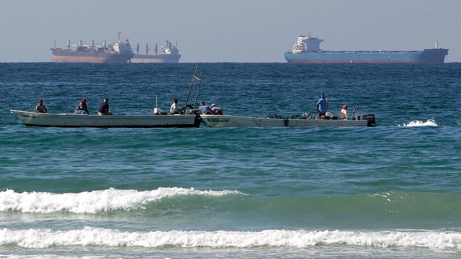 The passage of several oil tankers near fishermen's boats in the Strait of Hormuz
