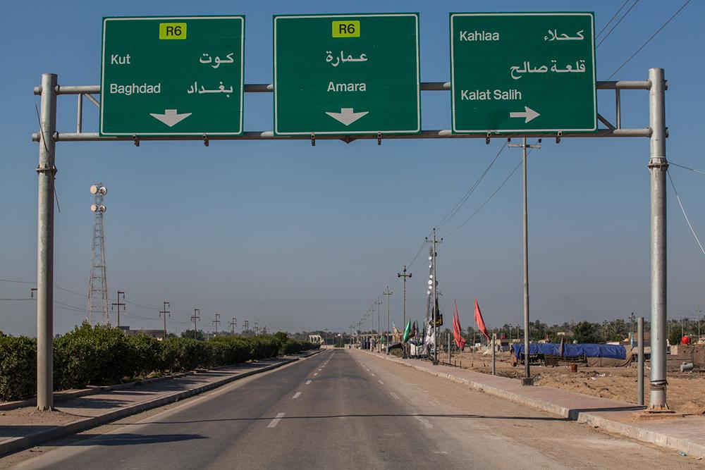 An overhead highway sign marks the route to Amara, the provincial capital of Iraq's Maysan Governorate. 

