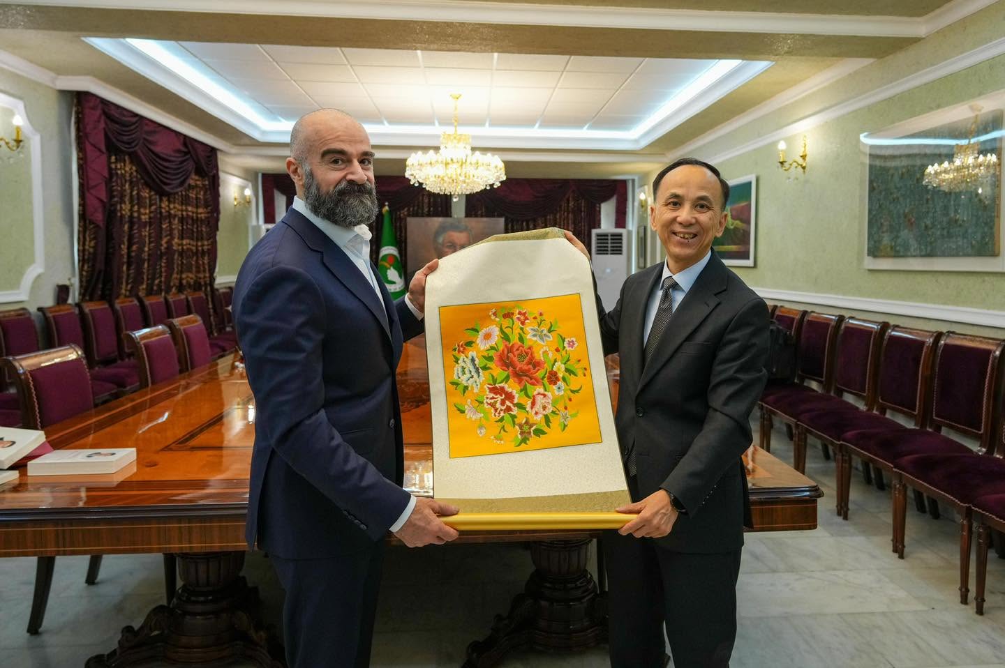 Patriotic Union of Kurdistan (PUK) President Bafel Jalal Talabani poses with Liu Jun, China’s Consul General in the Kurdistan Region, during a meeting in Slemani, Iraq, while holding an ornate traditional Chinese floral scroll painting presented as a cultural gift during diplomatic discussions