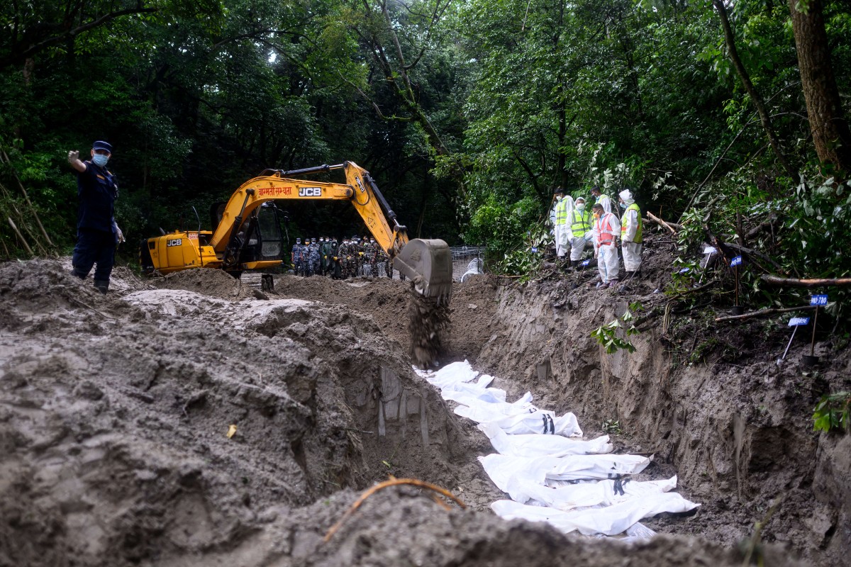 Security personnel conduct the mass burial of unidentified flood victims at the Gokarna forest reserve in Kathmandu on September 1, 2026. The death toll from devastating Himalayan glacial floods crossed the grim 1,000 mark on September 1, as Chinese and Nepali teams searched for survivors including dozens feared trapped in hydropower tunnels. (Photo by Manan VATSYAYANA / AFP)
