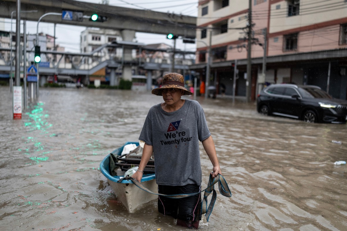 A man pulling a small boat wades through floodwaters in the Bang Bua district of Bangkok on September 26, 2026. Bangkok authorities declared a flood disaster across the Thai capital after almost 48 hours of heavy rain left canals full, roads submerged and residents wading through deep water. (Photo by WIKUS DE WET / AFP)