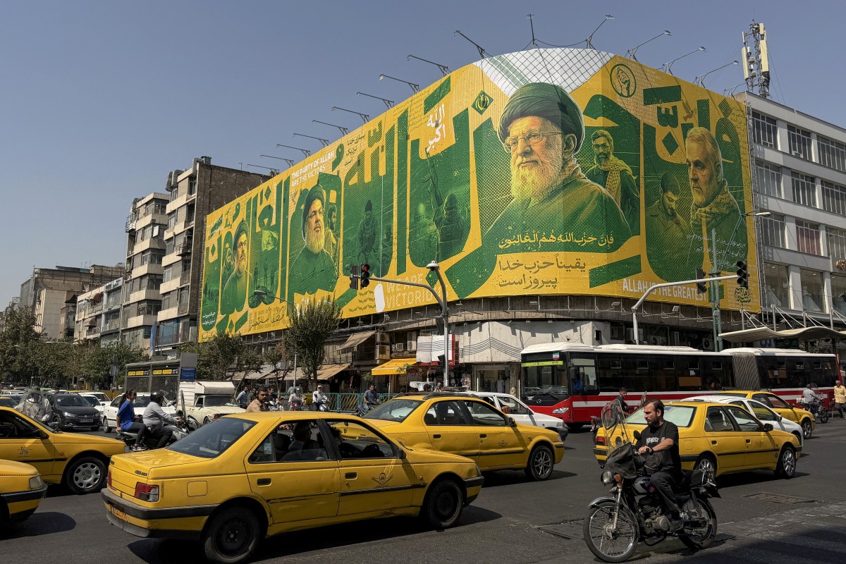 Iranians commute past a billboard depicting slain Lebanese Hezbollah leader Hassan Nasrallah and Iran's slain supreme leader Ayatollah Ali Khamenei in Tehran on September 27, 2026, on the second anniversary of Nasrallah's killing in a major strike by Israel on Beirut's southern suburbs. (Photo by ATTA KENARE / AFP) /