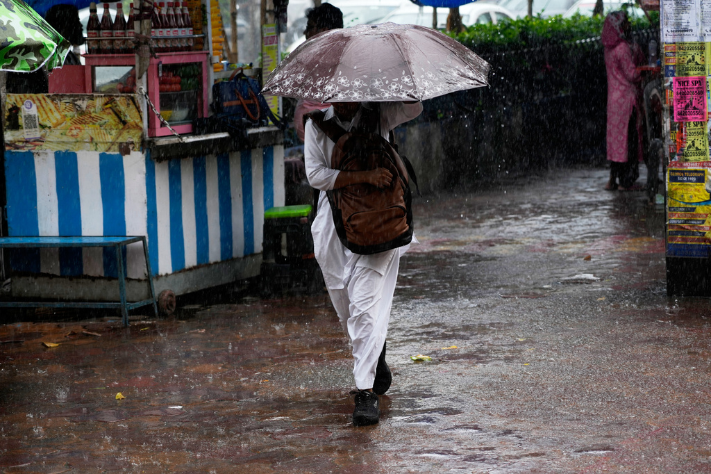 A commuter walks during a midday rain in Kolkata, India, Saturday, Sept. 26, 2026. (AP Photo/Bikas Das)