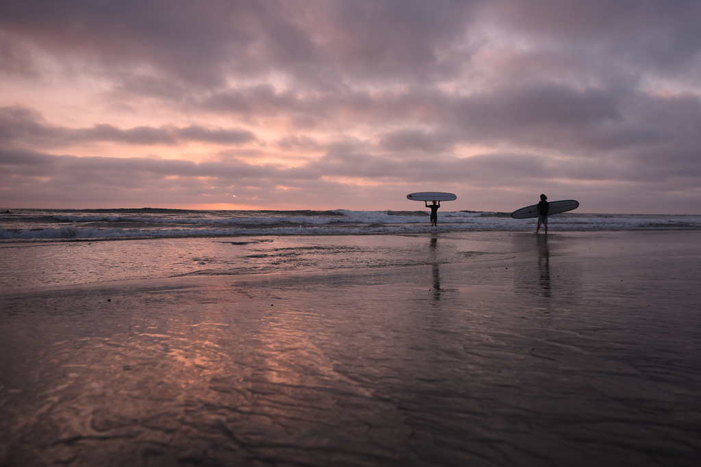 Surfers enter the Pacific Ocean as the sun sets Thursday, Oct. 1, 2026, in Encinitas, Calif. (AP Photo/Gregory Bull)