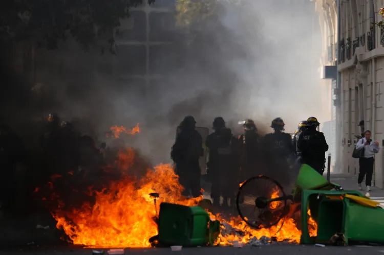 Policemen stand in front of burning garbage as they face students during a protest against under-resourced schools, in Paris, Friday, Oct. 2, 2026. (AP Photo/Aurelien Morissard)