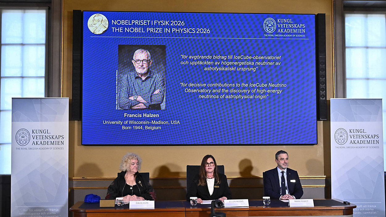 A portrait of Francis Halzen is shown on the screen as Eva Olsson, Ellen Moons, and Mark Pearce announce as the recipient of the 2026 Nobel Prize in Physics during a press conference at the Royal Swedish Academy of Sciences, Stockholm, Sweden, Oct. 6, 2026. (Christine Olsson/TT News Agency via AP)
