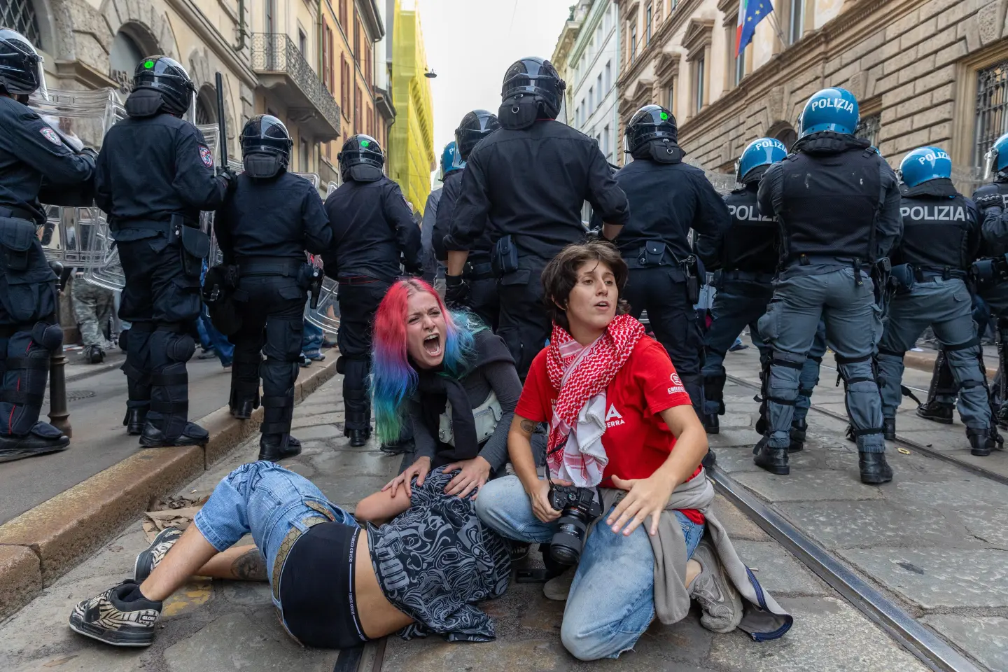 Demonstrators get shelter behind the police after clashes occurred during a protest against the high cost of living, in Milan, Italy, Saturday Oct. 17, 2026. (Stefano Porta/LaPresse via AP)
