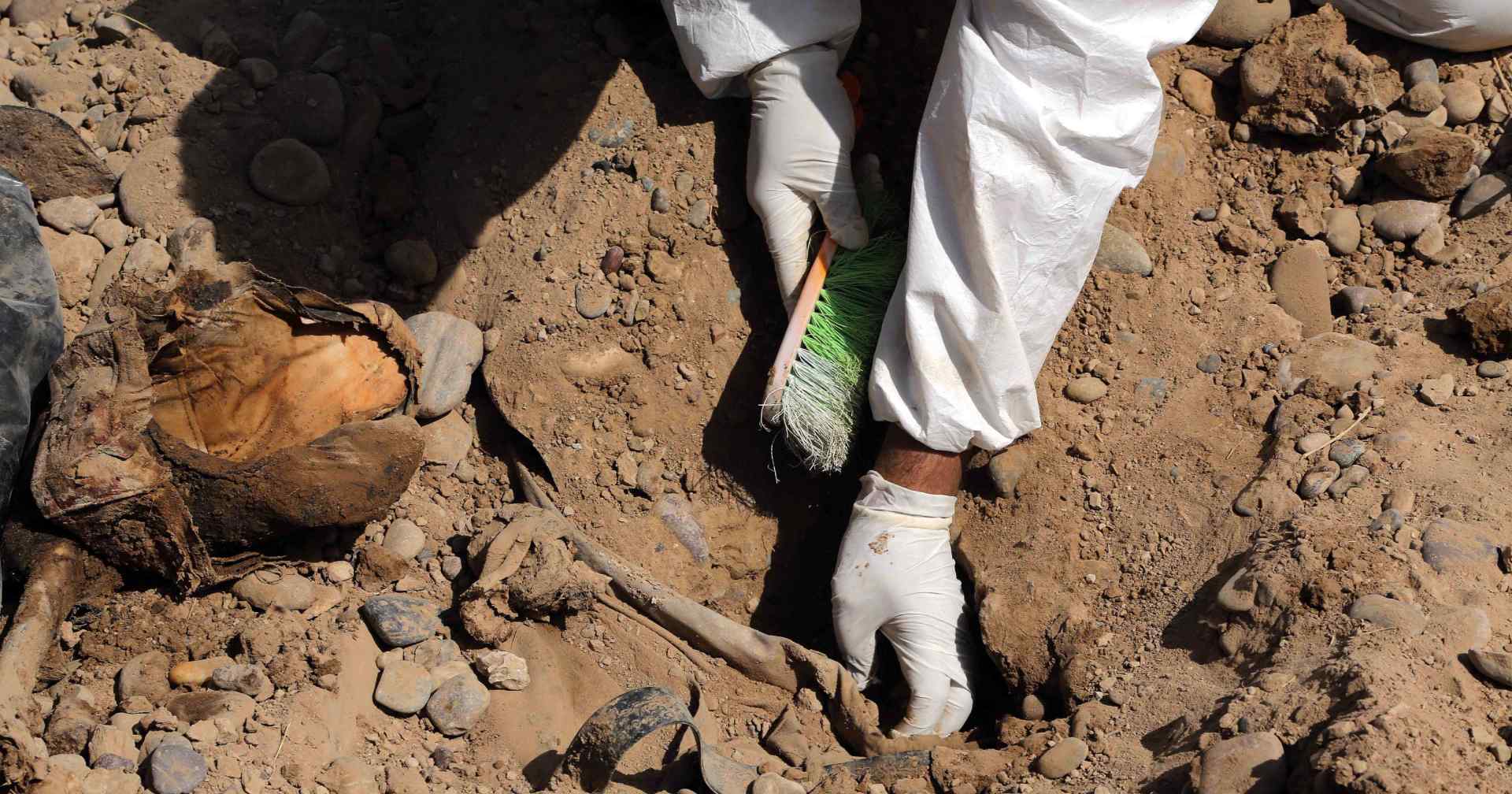 ئەندامێکى تیمەکانى هەڵدانەوەى گۆڕە بەکۆمەڵەکان، لە تکریت سەرقاڵى کارکردنە لە یەکێک لە گۆڕە بەکۆمەڵەکاندا. فۆتۆ: AP