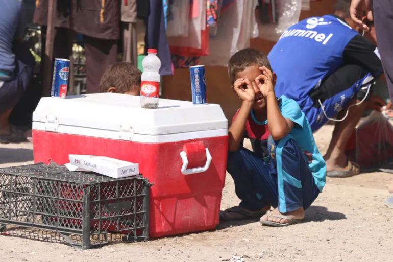 منداڵێکی عێراقی لە یەکێک لە شەقامەکاندا ئاو و ساردەمەنی دەفرۆشێت