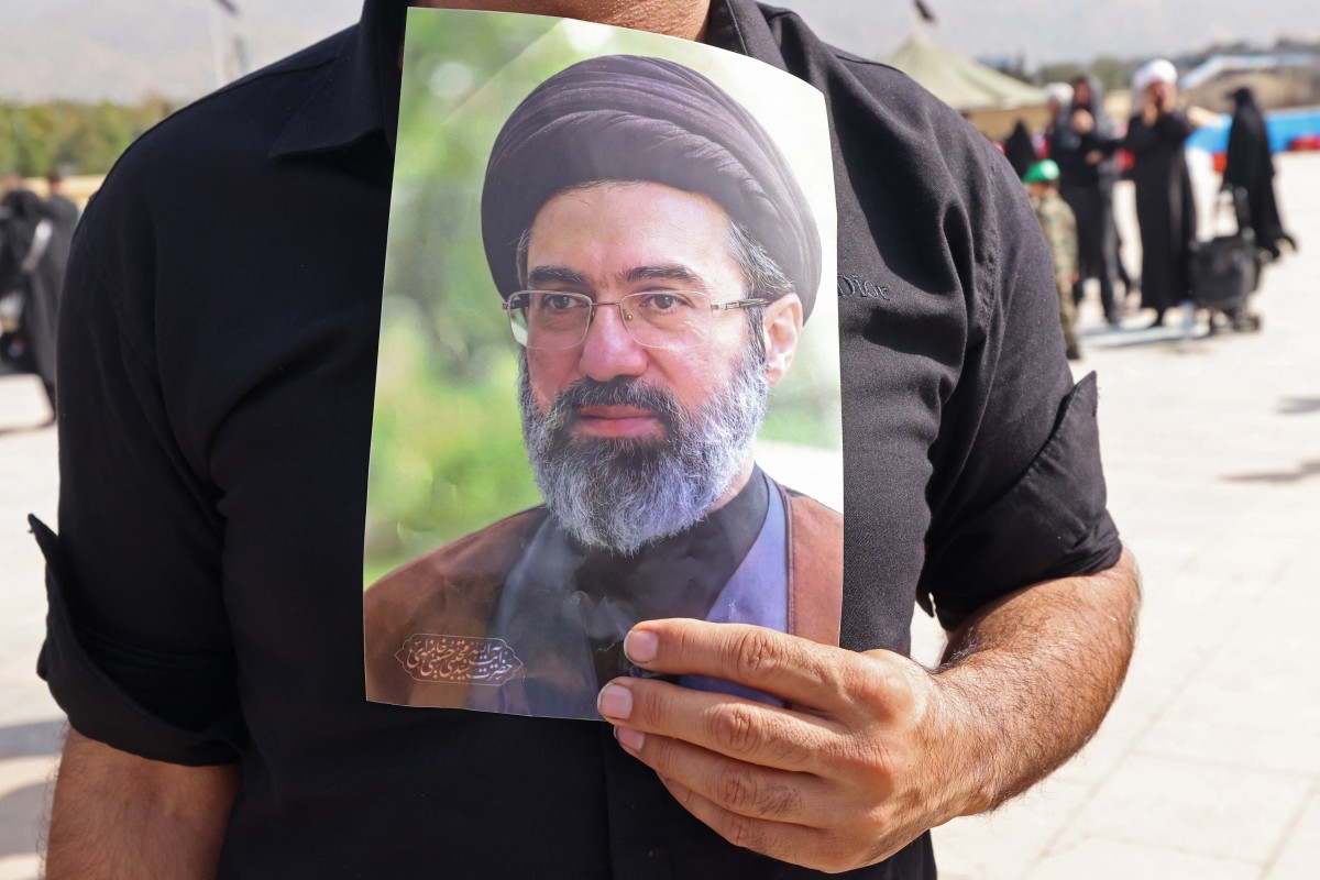 وێنەیەکی موجتەبا خامنەیی بە دەست یەکێک لە ماتەمگێڕانی ڕێوڕەسمی ماڵئاوایکردن لە تەرمی عەلی خامنەیی. فۆتۆ: AFP